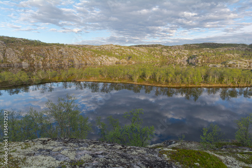 The reservoir is surrounded by hills and forest.Clouds are reflected in the water.Summer landscape.