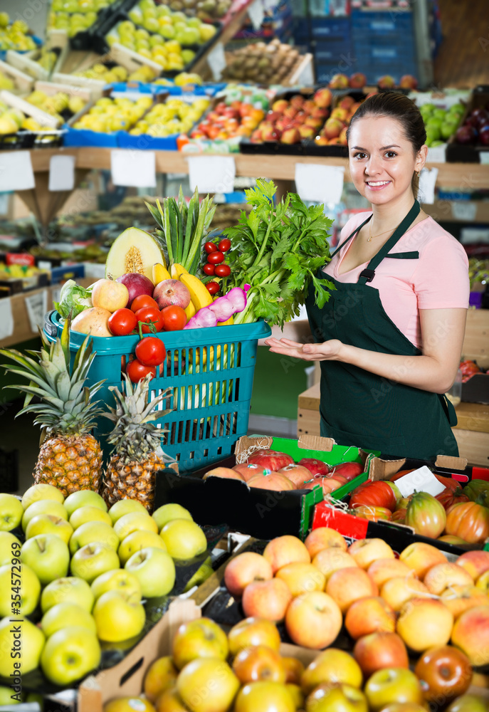 Saleswoman holding basket with greengrocery