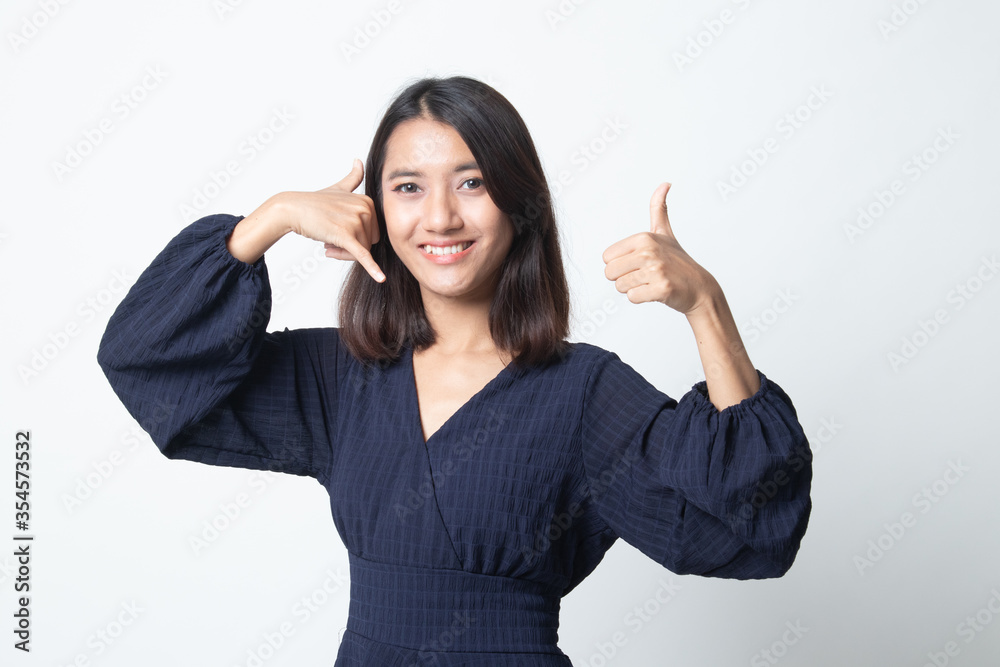 Young Asian woman thumbs up show with phone gesture. Young Asian woman thumbs up show with phone gesture.