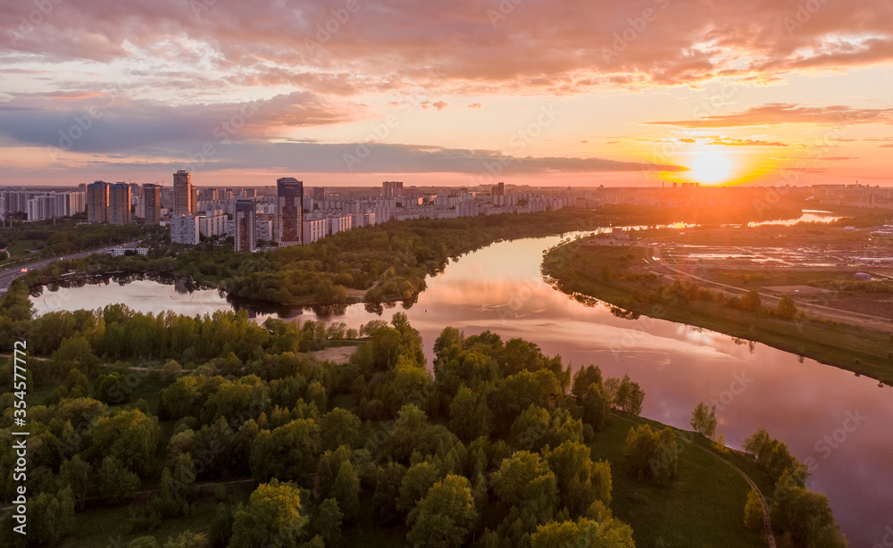 Beautiful sunset over the river against the background of the urban outskirts, in the frame nature and water. Aerial photography
