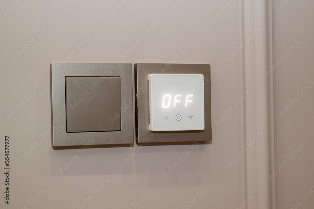 Close up view of electric light switch and sensor for floor heating on an empty wall Close up view of electric light switch and sensor for floor heating on an empty wall