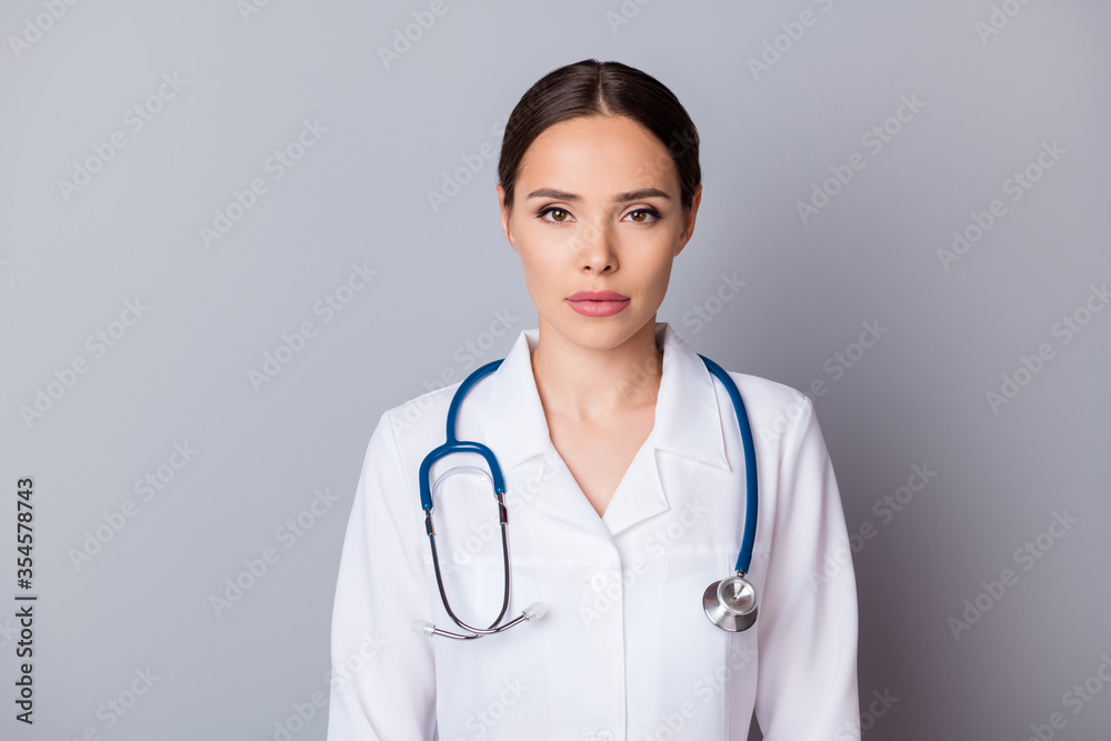 Portrait photo of attractive serious family doctor doc virologist not smiling experienced skilled professional wear medical gown lab coat stethoscope isolated grey background Portrait photo of attractive serious family doctor doc virologist not smiling experienced skilled professional wear medical gown lab coat stethoscope isolated grey background