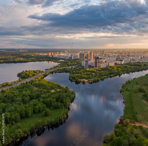 Beautiful nature in the city at sunset, the park and the river in the frame, in the background a residential area of the city. Aerial photography, golden hour