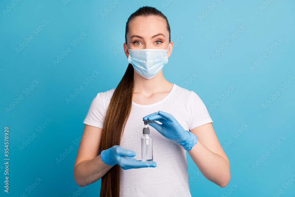 Photo of pretty cheerful lady hold hands antiseptic big bottle disinfection safety concept advising sterile hundred protection wear gloves face mask isolated blue color background Photo of pretty cheerful lady hold hands antiseptic big bottle disinfection safety concept advising sterile hundred protection wear gloves face mask isolated blue color background