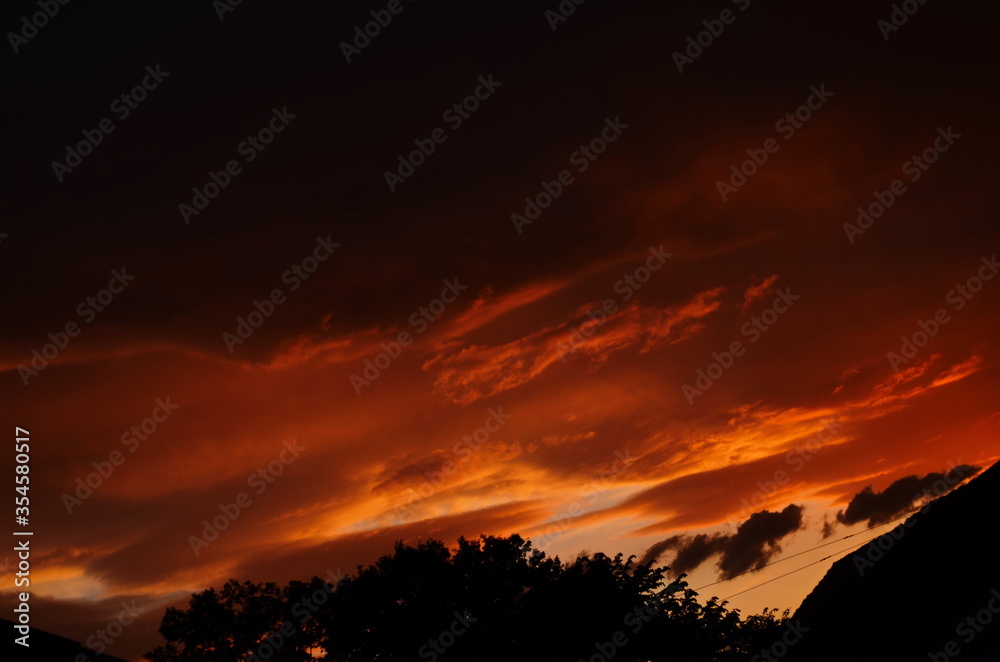 Golden sunset through wires over the roof of houses