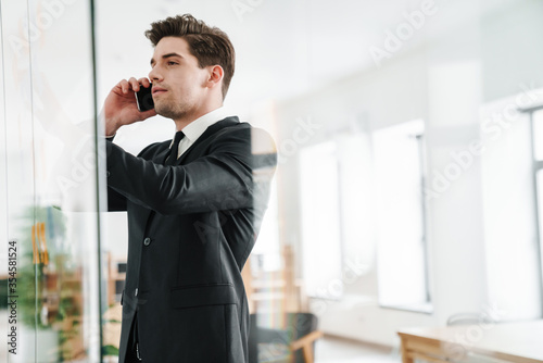 Image of concentrated businessman talking on cellphone while working