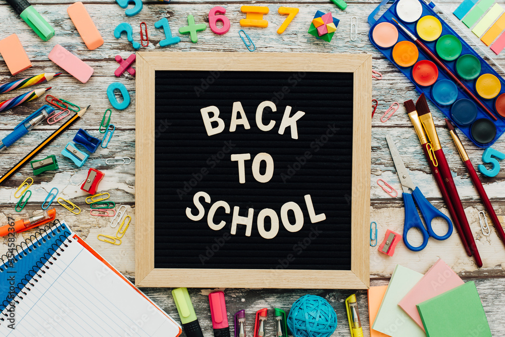 The words Back to School written in chalk on school desk with school supplies close-up. The words Back to School written in chalk on school desk with school supplies close-up.