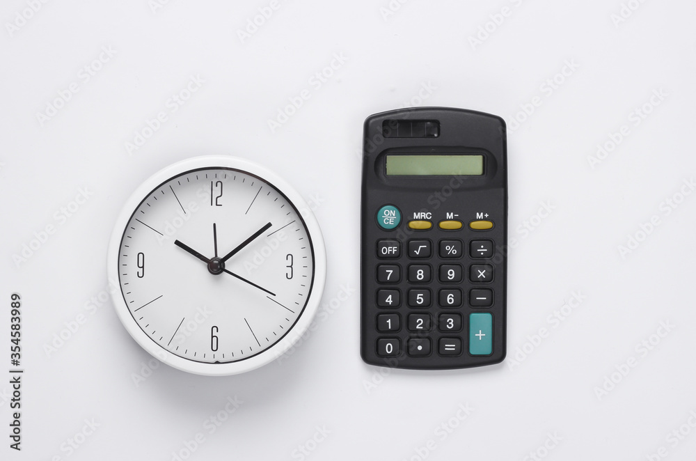 White clock and calculator on white background. Minimalistic studio shot. Top view White clock and calculator on white background. Minimalistic studio shot. Top view