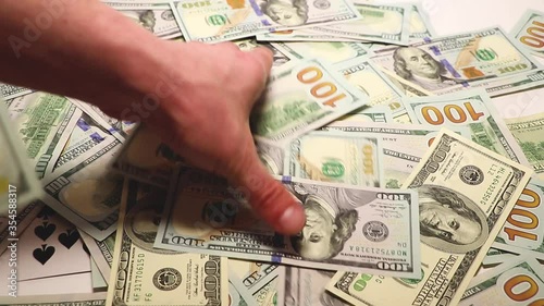A man's hand collects one hundred dollar bills from the table. Winning cards. Many dollars.