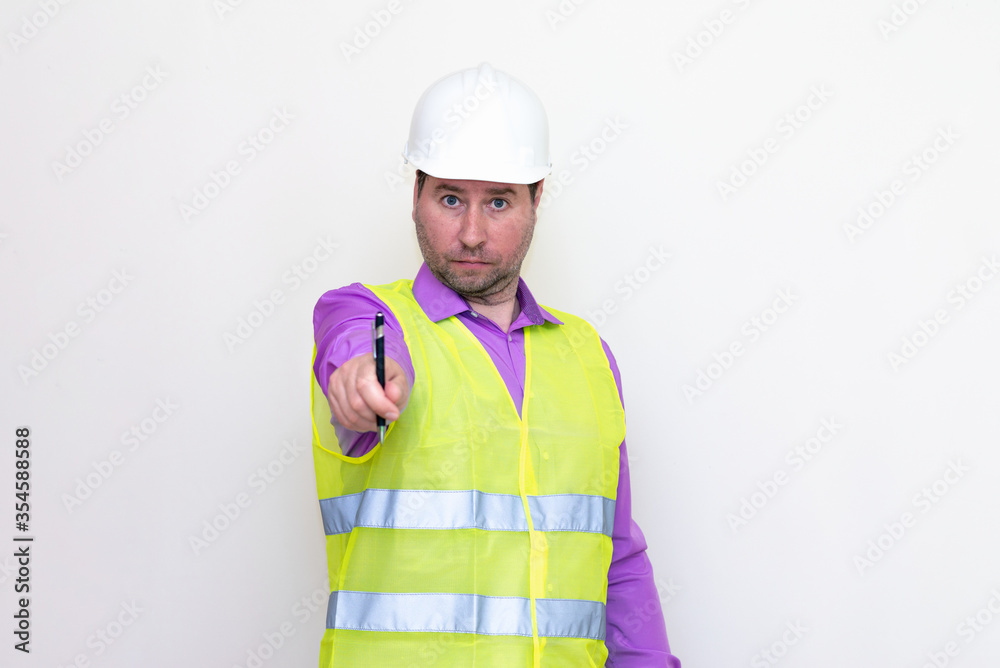 Portrait middle age of caucasian worker wearing hard hat holding pen makes all kinds of grimaces on white studio background.