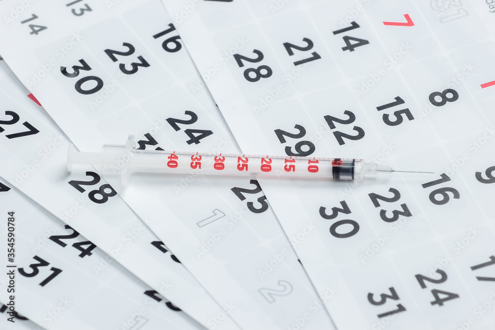 Syringe on a monthly calendar close-up. Vaccination Syringe on a monthly calendar close-up. Vaccination