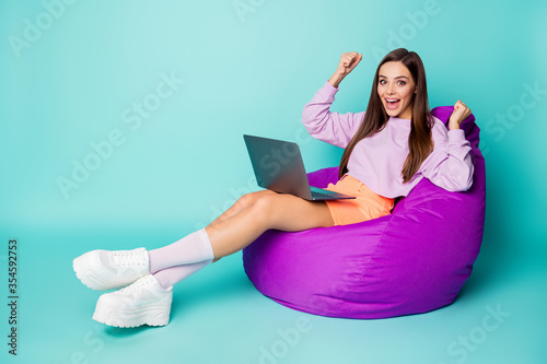 Full size profile photo of crazy excited lady sit comfy bean bag chair hold notebook work home first salary wear purple sweater orange skirt sneakers socks isolated teal color background