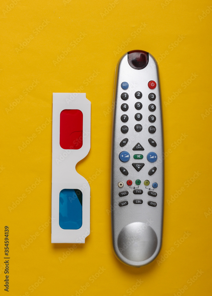 Anaglyph disposable paper 3d glasses and tv remote on yellow background. Tv time. Top view Anaglyph disposable paper 3d glasses and tv remote on yellow background. Tv time. Top view