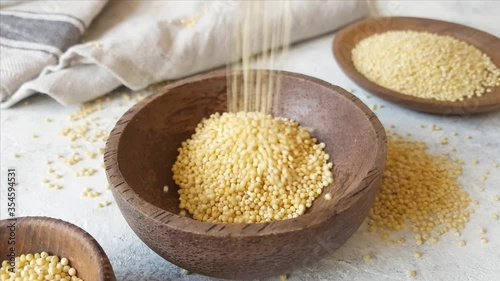 Raw dry hulled millet in a bowl with a spoon