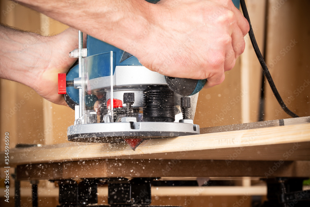 closeup of carpenter with hand wood router machine at work. closeup of  routing bevel into plank of pine woodworking construction tool concept  furniture making diy background Stock Photo | Adobe Stock