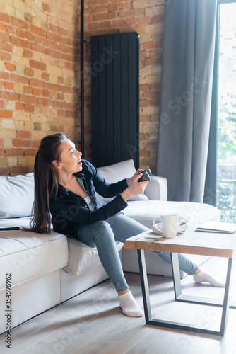 KYIV, UKRAINE - APRIL 29, 2020: happy young woman holding joystick while playing video game in living room