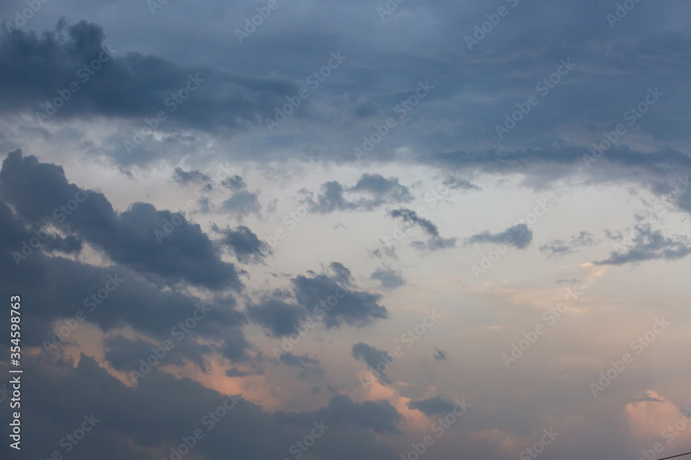 Beautiful dramatic gray and white clouds on blue sky, variety of shapes, silhouettes and shades at sunset time Beautiful dramatic gray and white clouds on blue sky, variety of shapes, silhouettes and shades at sunset time