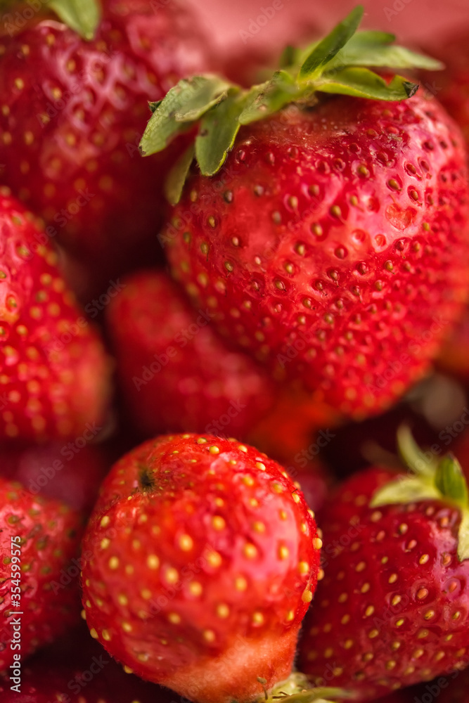 Strawberry. Vertical macro closeup of fresh red and ripe strawberries. Vegetarian vegan organic berries macro. Fruit background. Freshly harvested strawberries. Selective focus
