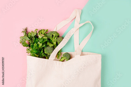 Reusable shopping bag full of groceries on color background