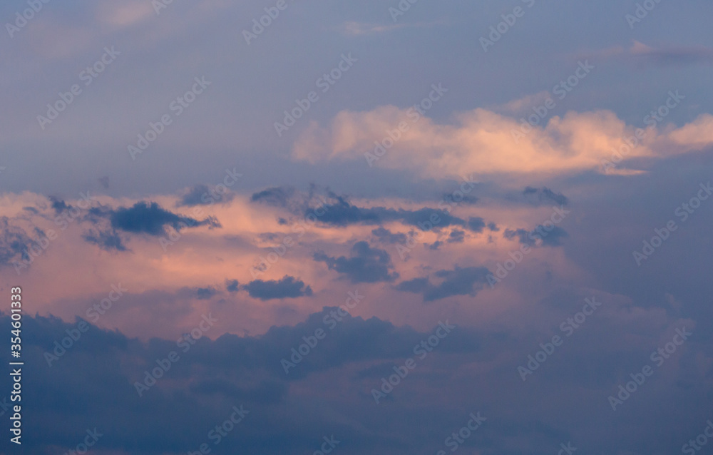 Obraz premium Beautiful dramatic gray and white clouds on blue sky, variety of shapes, silhouettes and shades at sunset time