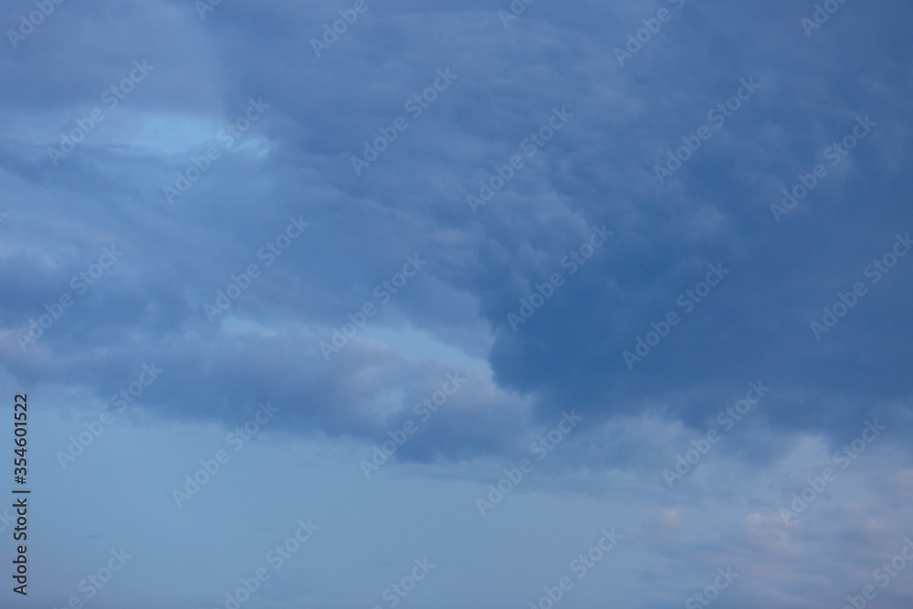 Beautiful dramatic gray and white clouds on blue sky, variety of shapes, silhouettes and shades at sunset time