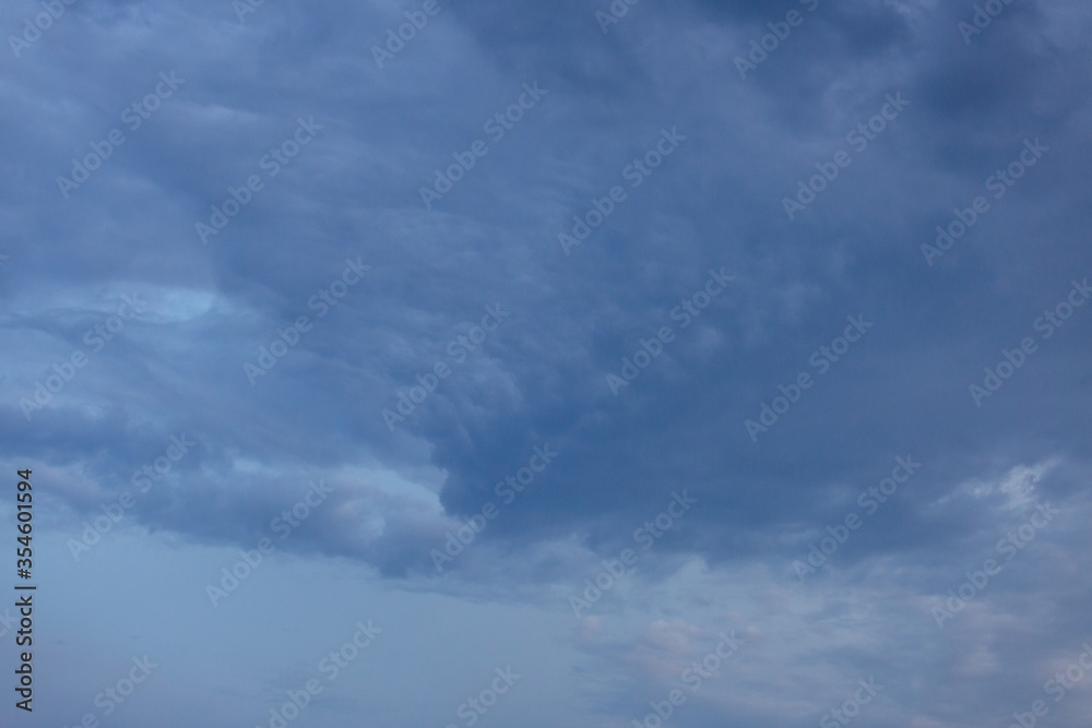 Beautiful dramatic gray and white clouds on blue sky, variety of shapes, silhouettes and shades at sunset time Beautiful dramatic gray and white clouds on blue sky, variety of shapes, silhouettes and shades at sunset time