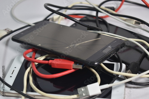 Closeup of old broken mobile phones with charging Cables and USB cables wires E-waste pollution 