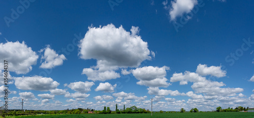 Panorama of open field with fluffy white clouds against a blue sky. Perry Green, Much Hadham, Hertfordshire. UK photo