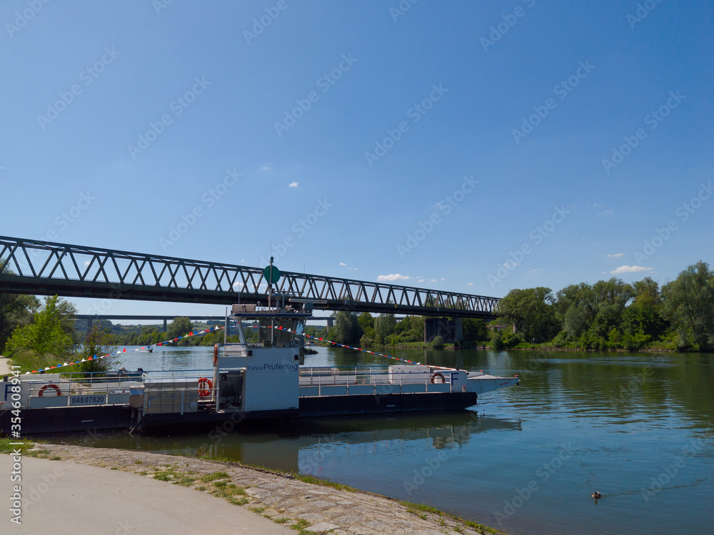 Car ferry boat at pier with railway bridge in background  on sunny day near Regensburg, Bavaria, Germany