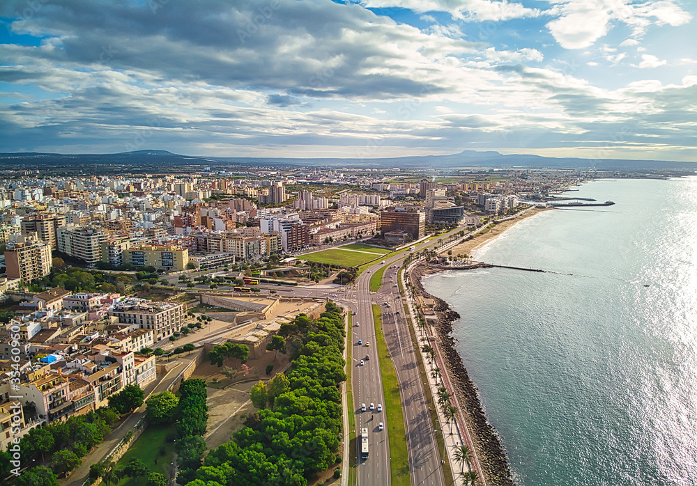 Aerial panorama Palma de Mallorca cityscape. Urban scene with roads along palm tree lined seafront tranquil Mediterranean Sea. Cloudy sky over townscape picturesque landscape. Balearic Islands, Spain