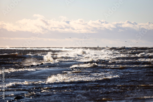 Windy late evening sunset view to Baltic sea lighthouse with large storm waves.