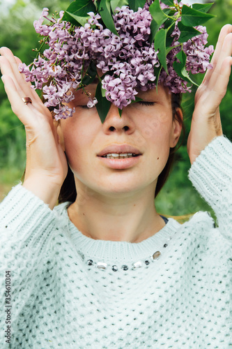 Beautiful woman with lilac flower wreath. Girl in a wreath of lilac in the spring.