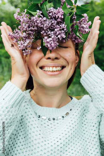 Beautiful woman with lilac flower wreath. Girl in a wreath of lilac in the spring.