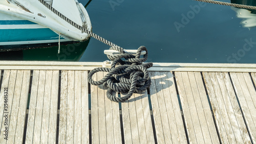 Black rope tied to the bollard and white Board berth