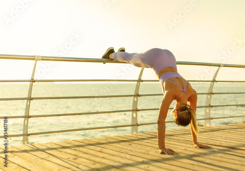 Morning workout concept. Young fit woman in sportswear doing push-up exercise at sunrise on beach