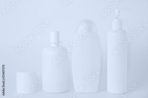 White plastic bottles with cosmetics on white background.