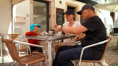 Family with small boy drinking and talking in cafe in Lagos, Portugal
