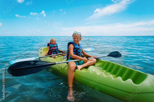 happy girl and boy kayaking on beach vacation