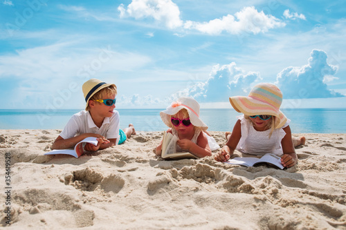 Foto happy kids -boy and girls- read books on beach, summer reading on vacation