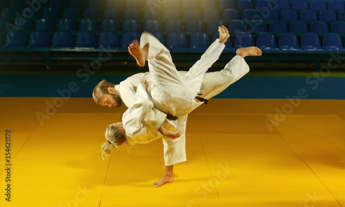 Martial arts. Sparing Portners. Sport man and woman in white kimono train judo throws and captures in the sports hall
