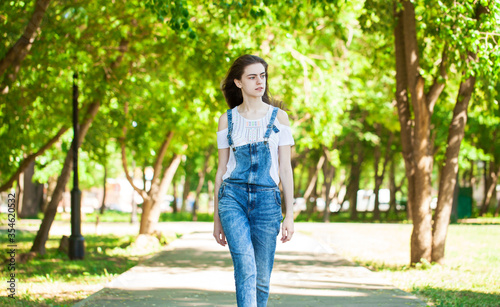 Portrait of a young beautiful teenager girl in blue jeans overalls