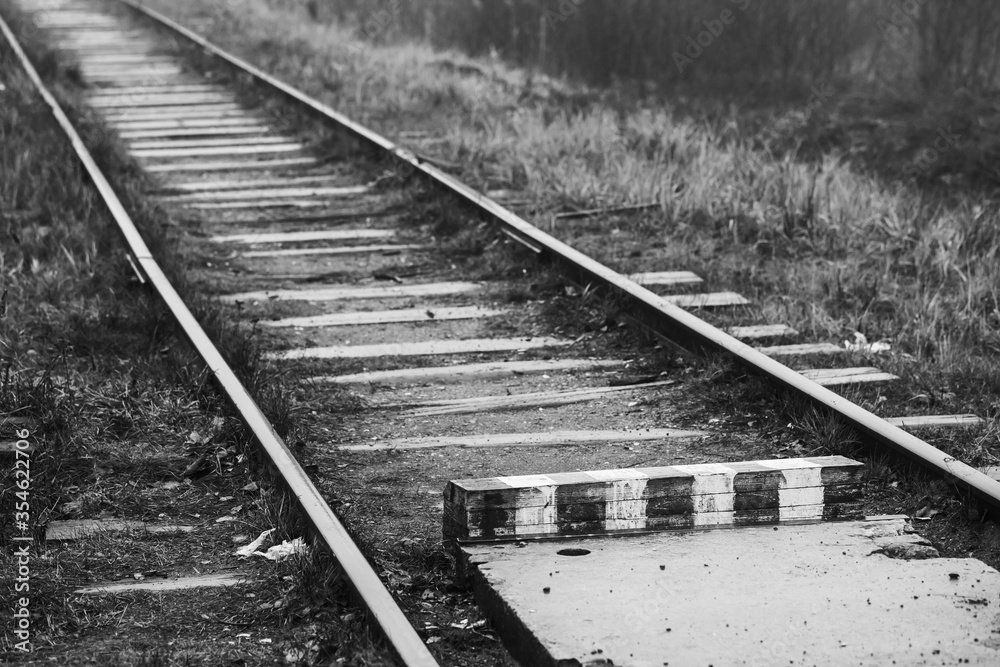 Empty railway and striped wooden border sign