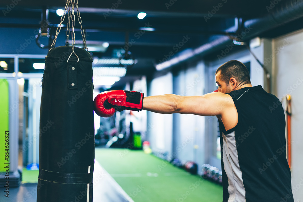 Latin boxer with red gloves hitting sack with the left