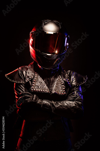 Portrait of a young female biker wearing a studded leather jacket and a black helmet