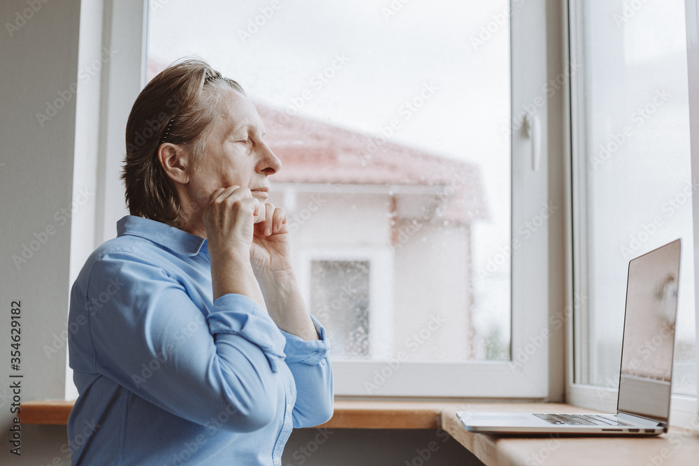 Prevention of aging. An adult woman is engaged in strengthening facial muscles on-line lessons at home during the quarantine in connection with the coronavirus epidemic. Prevention of aging. An adult woman is engaged in strengthening facial muscles on-line lessons at home during the quarantine in connection with the coronavirus epidemic.