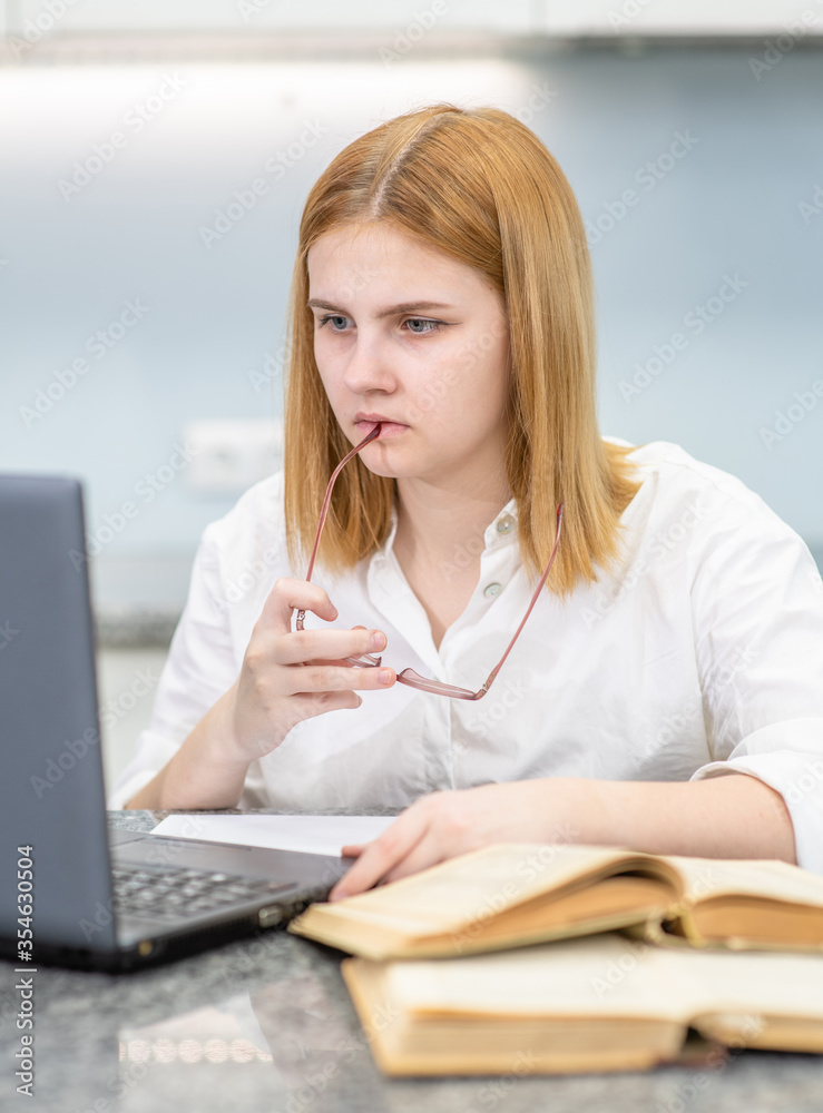 Pensive girl uses laptop at home. Distance learning concept concept Pensive girl uses laptop at home. Distance learning concept concept