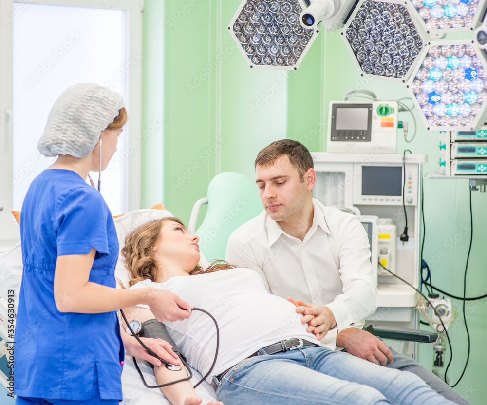 Nurse checks the health of a pregnant woman before giving birth in an operating room Nurse checks the health of a pregnant woman before giving birth in an operating room