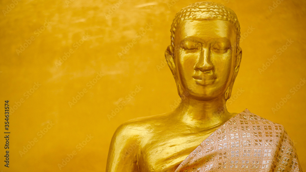 Golden Buddha statue on golden wall background