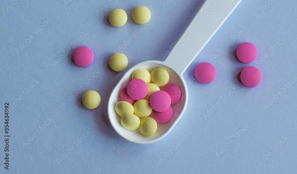 Colored pills on the table. Medical drugs on a blue background. Place for text. Colored pills on the table. Medical drugs on a blue background. Place for text.