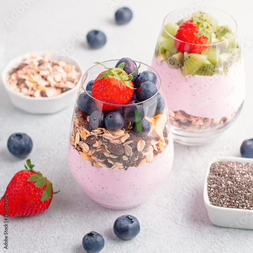 Chia seeds pudding with granola, blueberry and strawberry in glasses. Yogurt with chia seeds, berries, kiwi and muesli for healthy breakfast, copy space